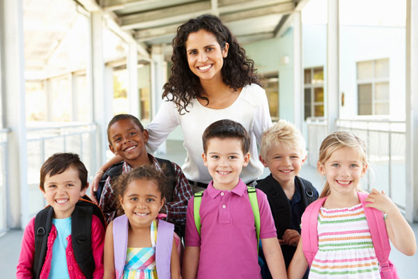 Elementary teacher posing with a group of her students outside a school