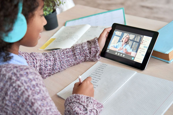 Middle school student watching a lesson from her teacher on a tablet