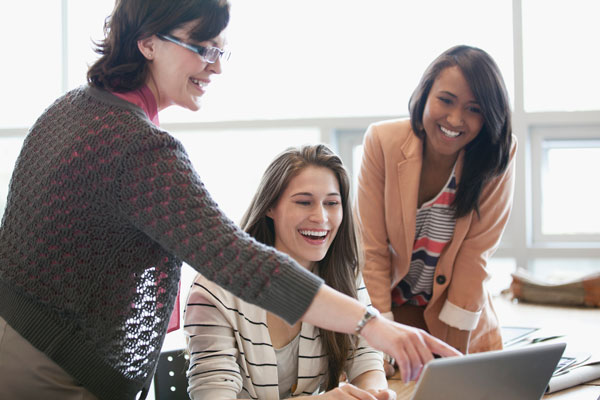 Three teachers looking at a laptop together