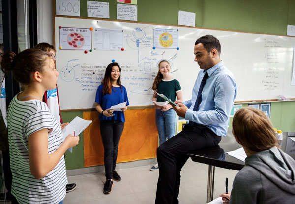 Group of students presenting in to their science teacher