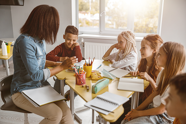 Teacher working with elementary students at a round table