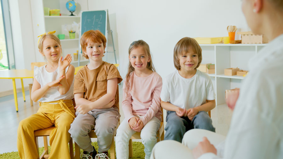 A group of young students sitting and listening to their teacher