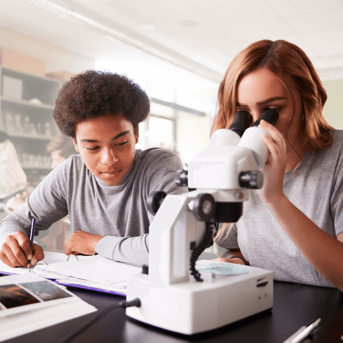 Two high school students take turns looking through a microscope